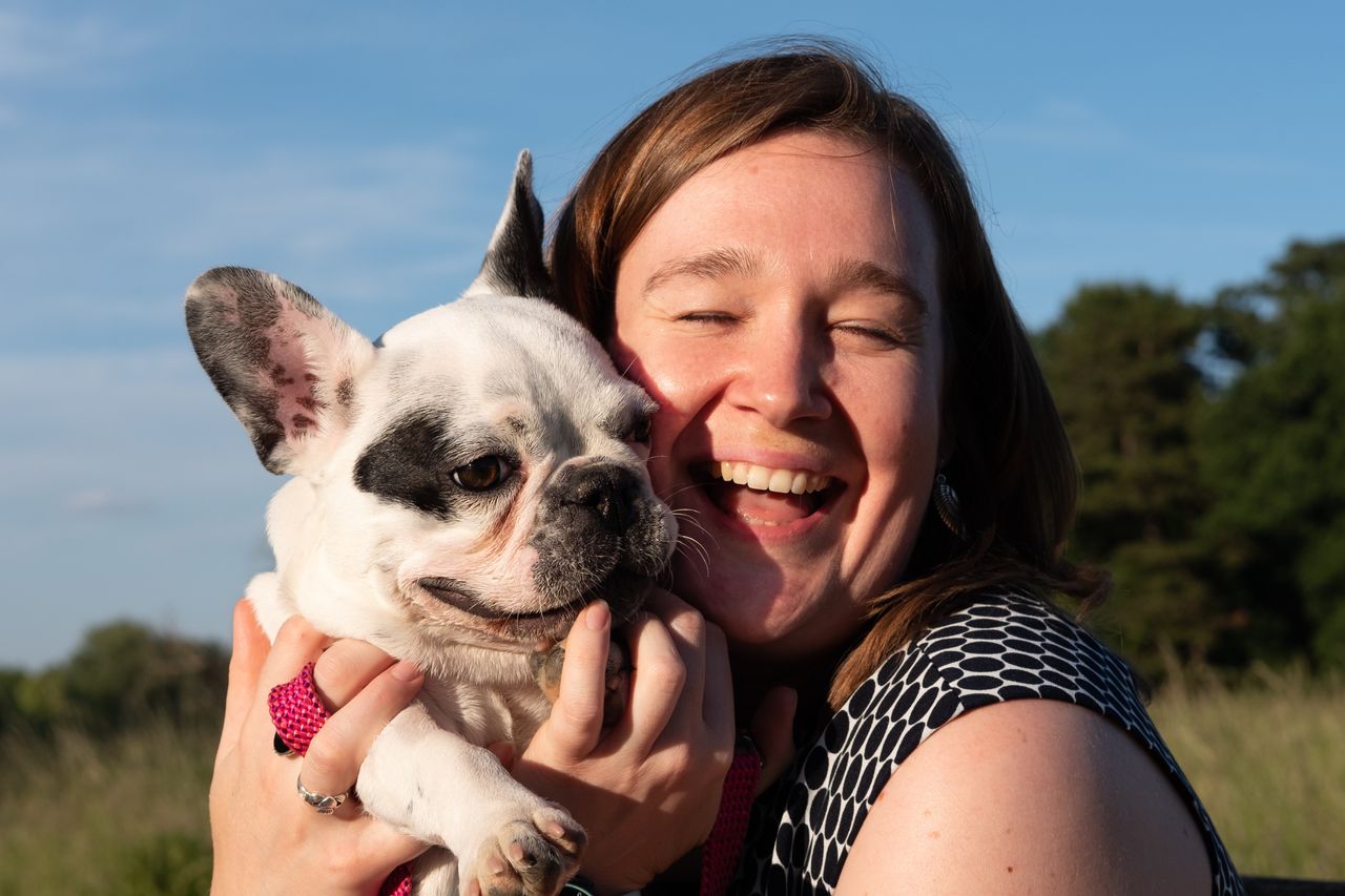 A girl holding a French Bulldog puppy