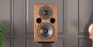 AE1 40th Anniversary speaker in walnut on a stand next to a cello and green plant