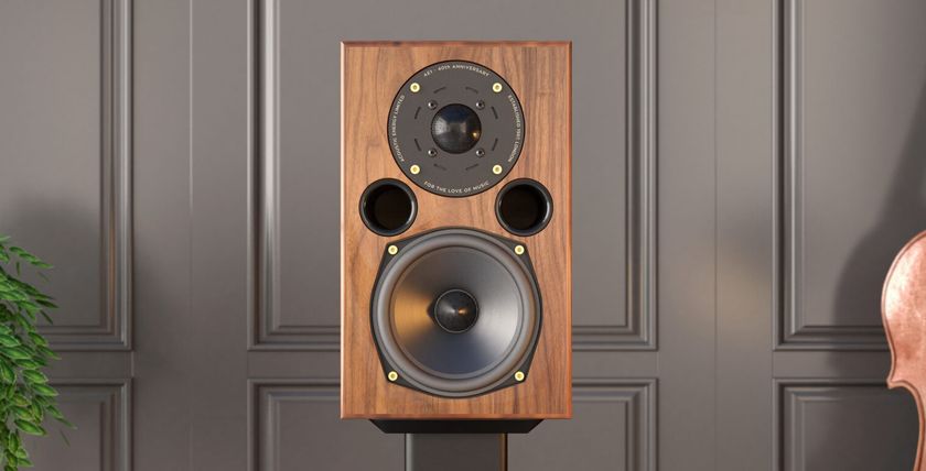 AE1 40th Anniversary speaker in walnut on a stand next to a cello and green plant