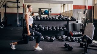 Woman performs lunge holding dumbbells