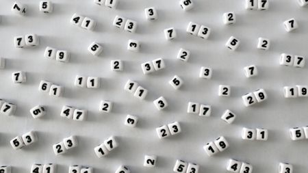 Single and double digit prime numbers are represented on the faces of scattered dice.