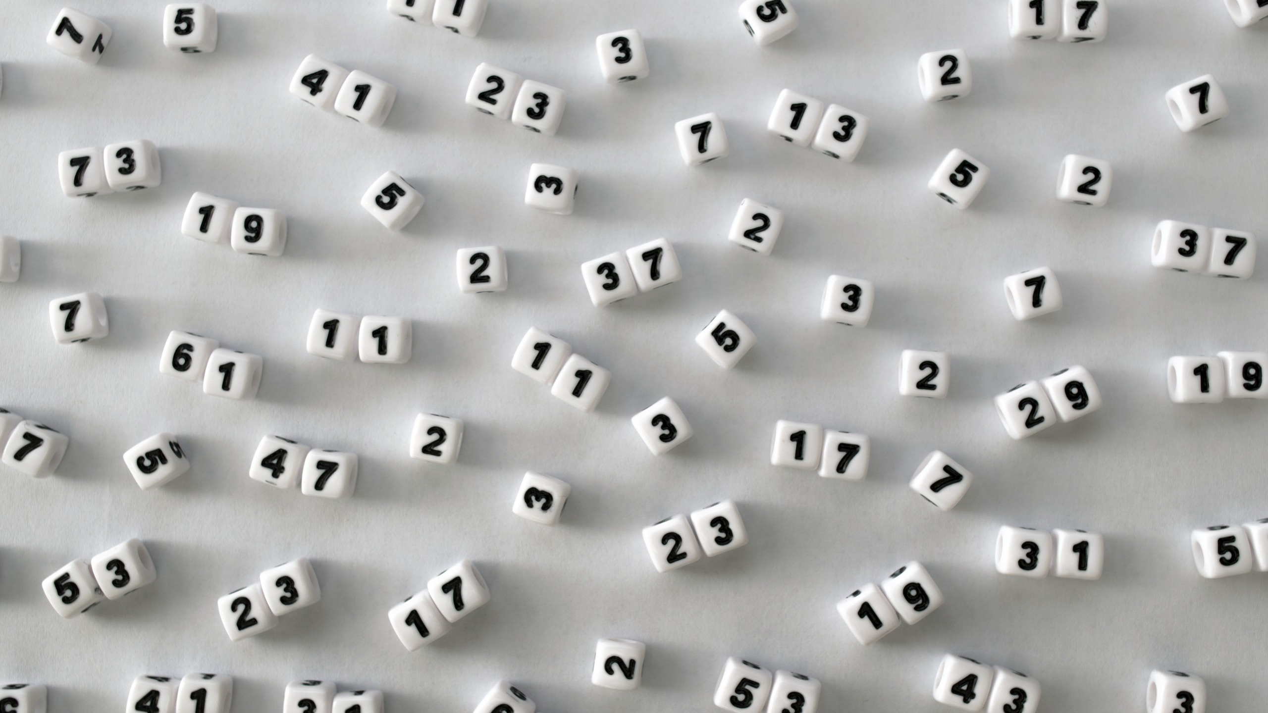 Single and double digit prime numbers are represented on the faces of scattered dice.
