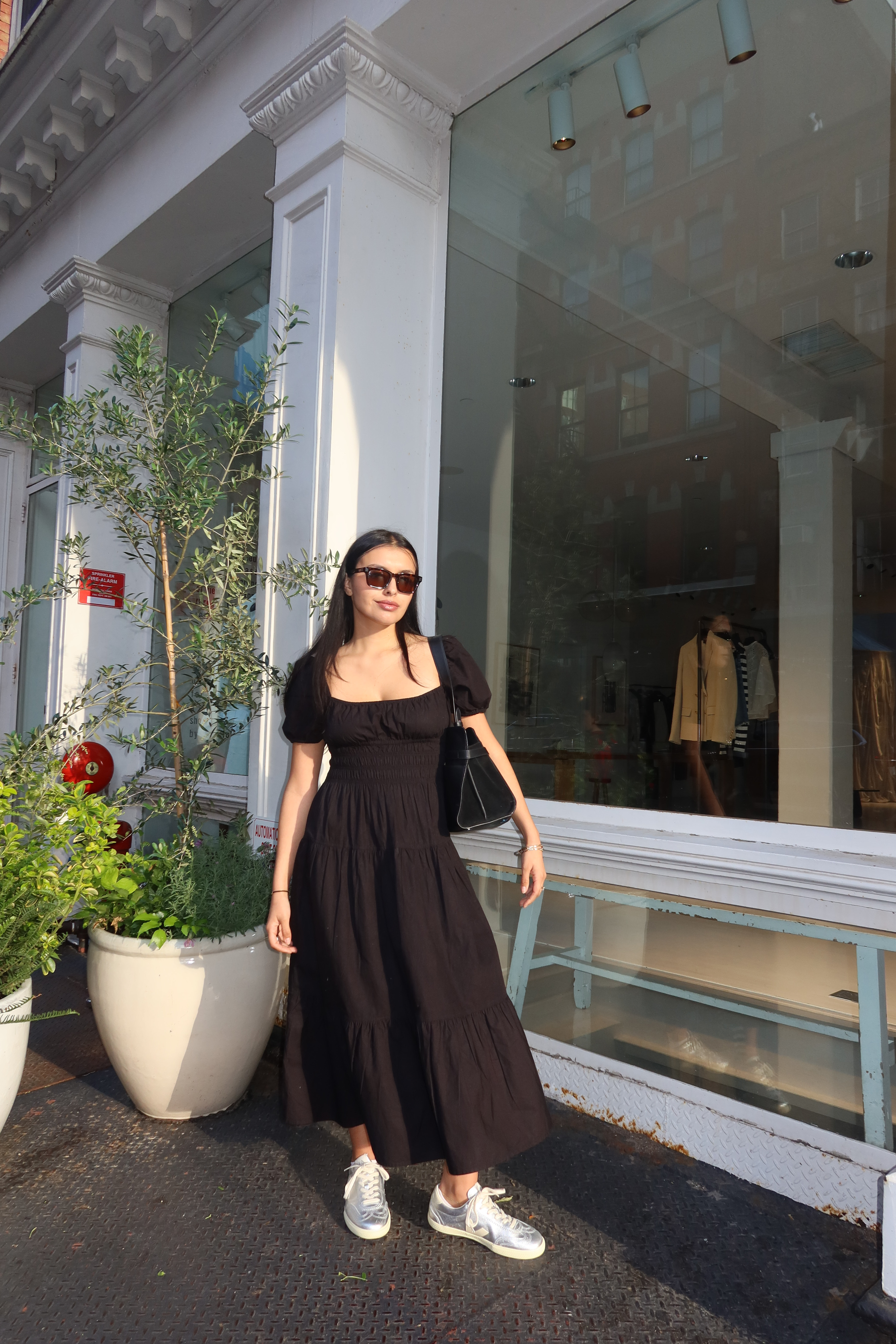 Renata D'Agrella wearing a black dress and silver sneakers.