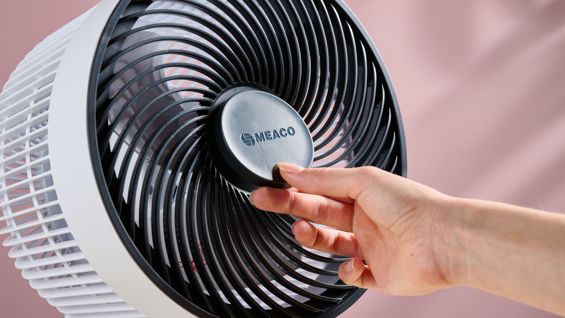 The circular remote is being placed back in the center of the fan's grill.