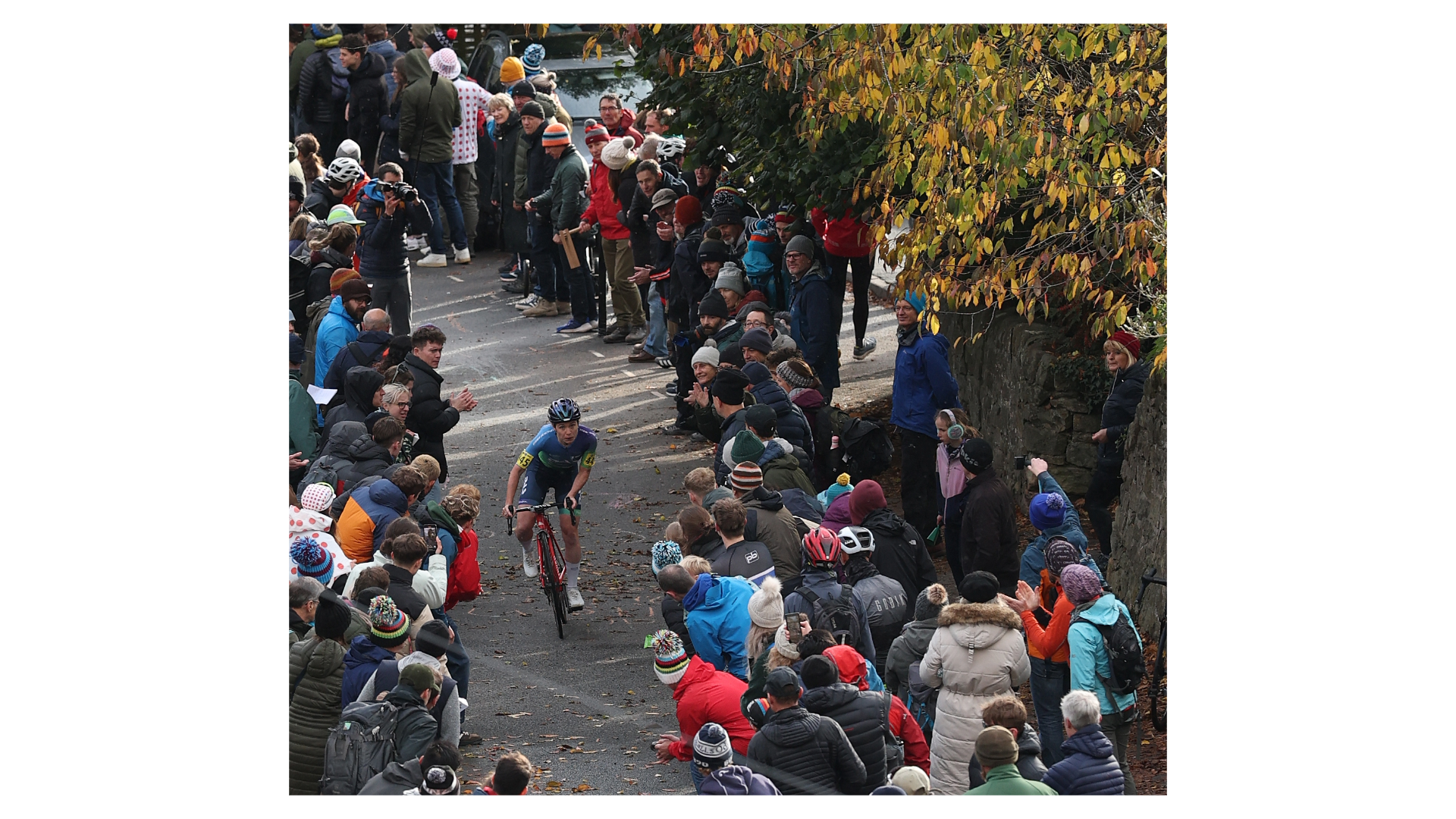 Woman cycles up hill with crowds