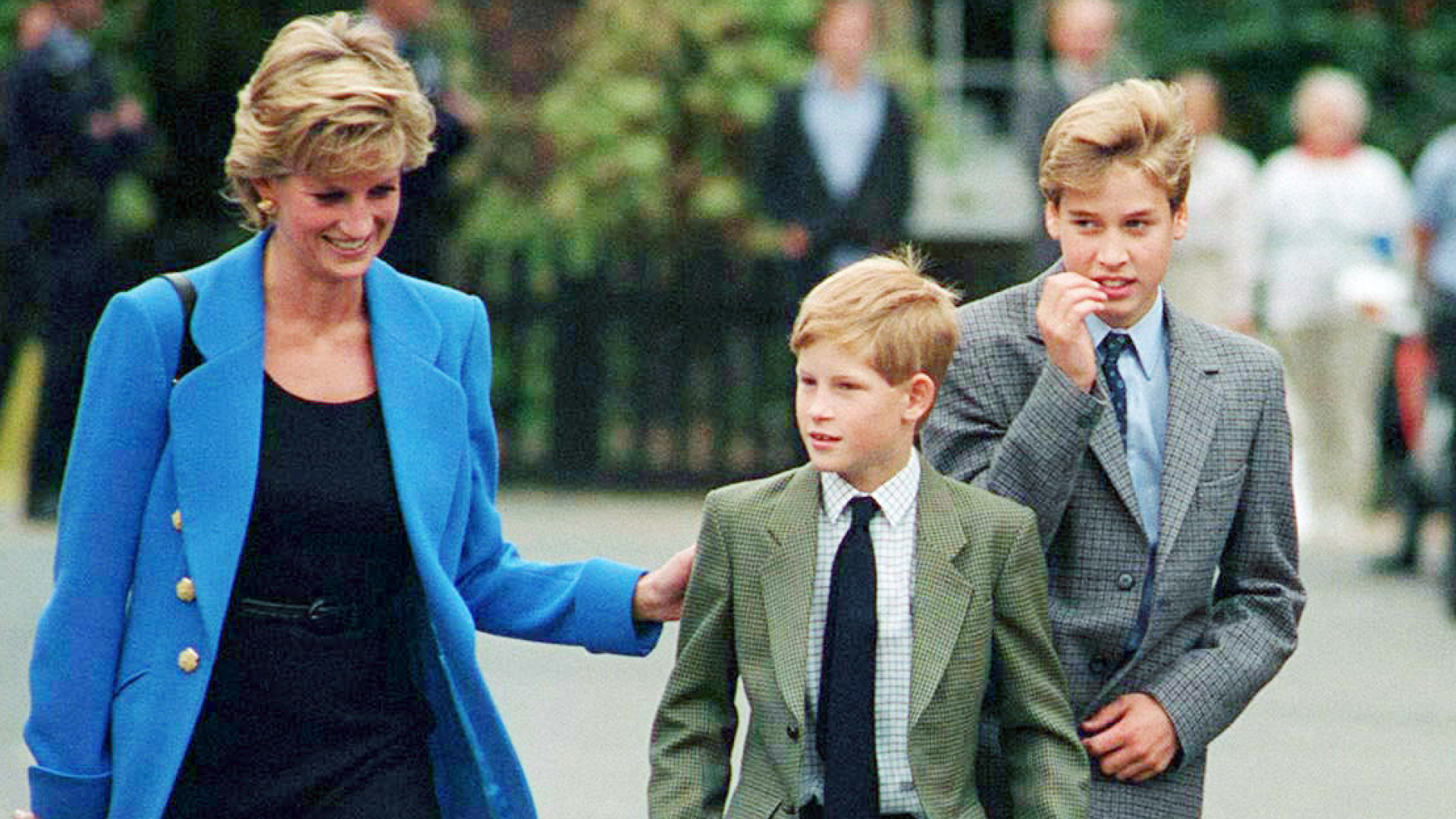 Princess Diana, Prince Harry and Prince William walking outside at Eton College in suits