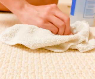 hand using cloth to mop up spillage on carpet
