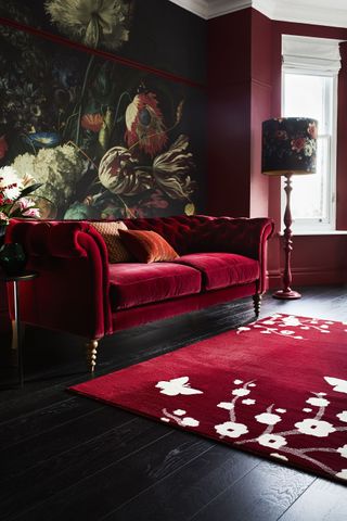 luxurious living room with deep red scheme and dark floral wall mural as a great example of how to mix pattern and prints in interiors by carpetright