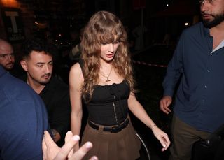 Taylor Swift spotted in Sydney, Australia, wearing a black corset top and pleated skirt