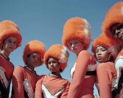 Drum majorettes in orange uniforms and fluffy hats.