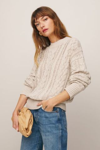 reformation winter sale woman wearing cream cable knit jumper