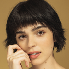 a close up of a woman care face with bushy eyebrows and a short haircut