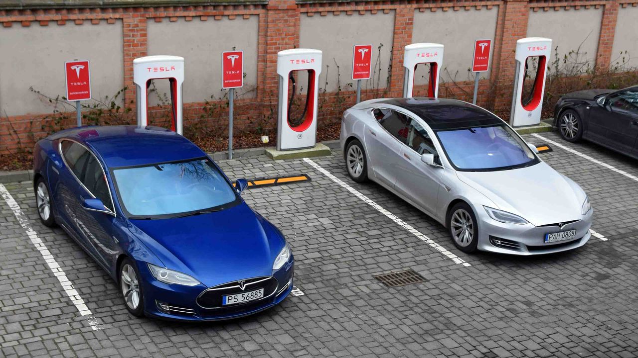 Two Teslas charging in a parking lot