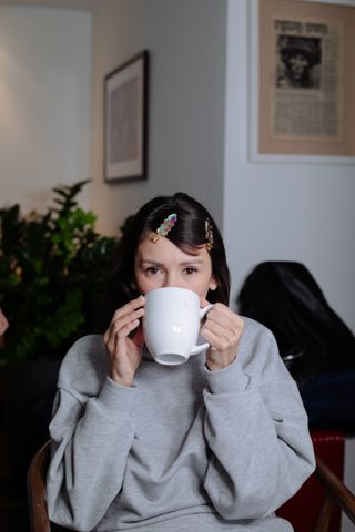 Nina Dobrev sips a cup of coffee while getting ready for the Carolina Herrera show