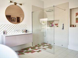 Pink bathroom with walk in shower and round copper mirror