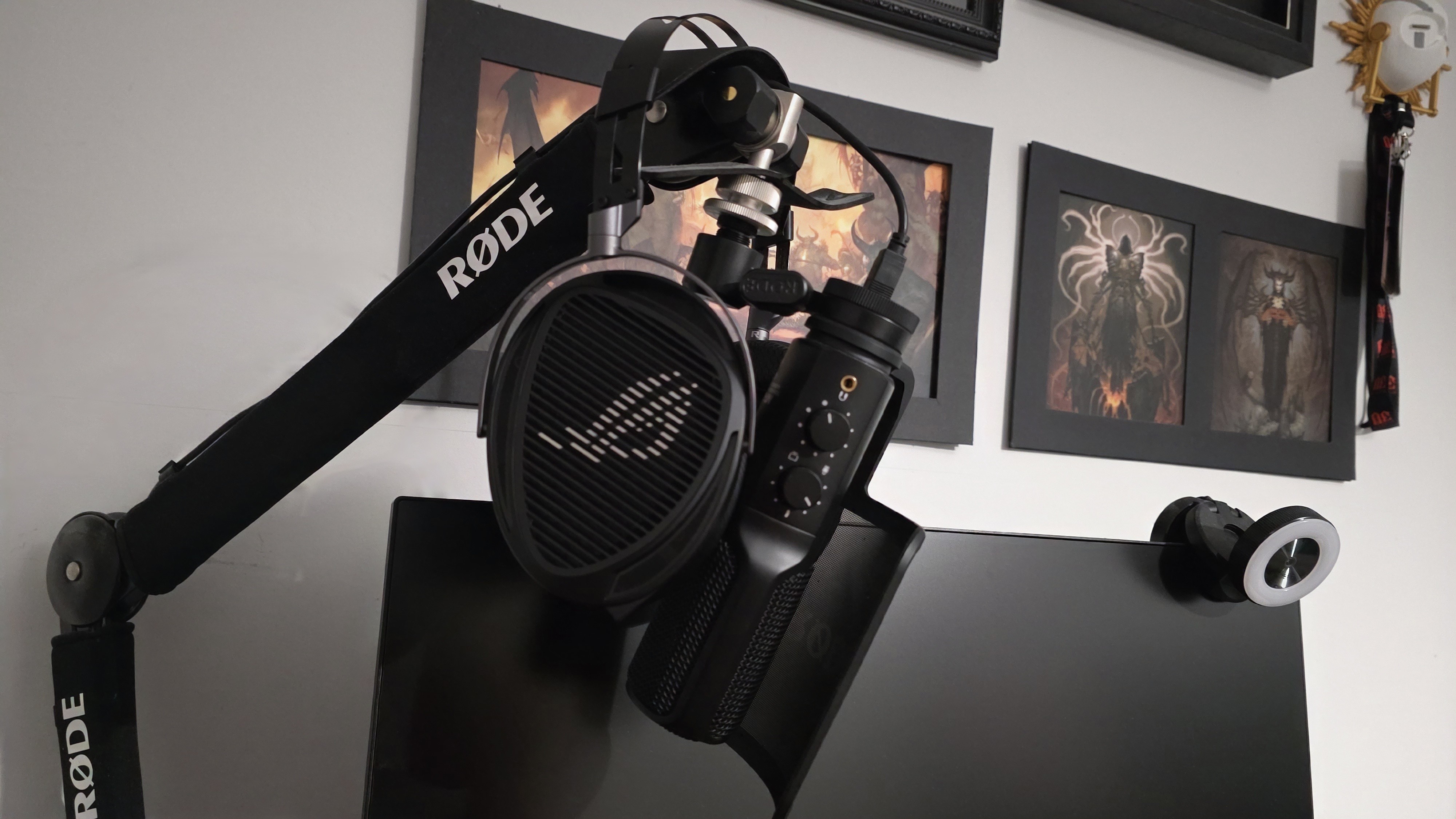 A RODE microphone and ASUS headset are mounted on an articulated arm in front of a monitor. The background features framed Diablo artwork.