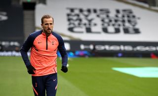 Harry Kane warms up for Tottenham in front of a banner reading