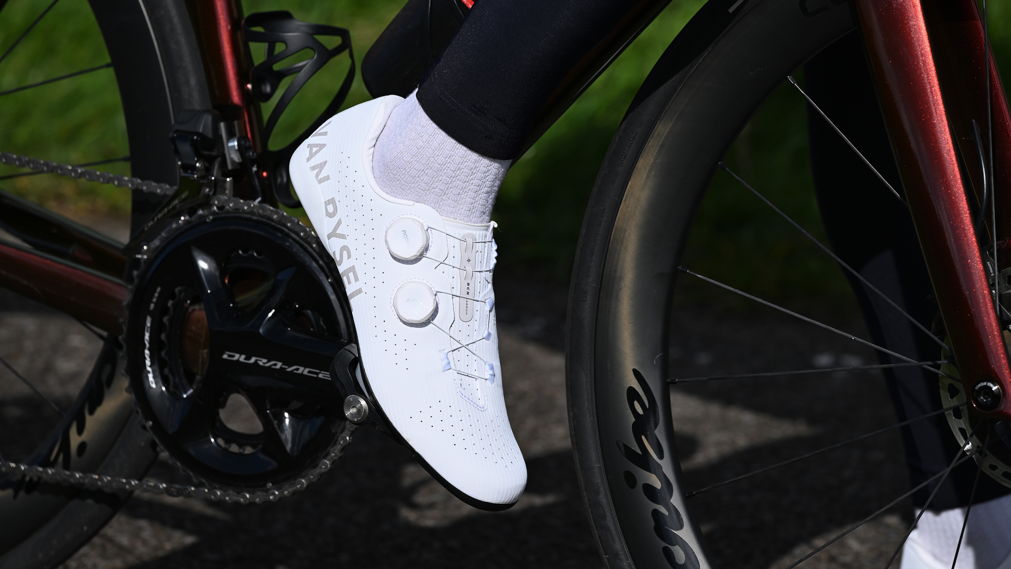 Close up of a white cycling shoe clipped into a road pedal