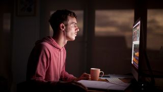 A man working on his computer late at night wearing headphones