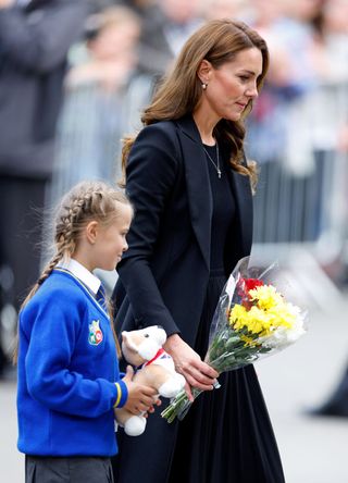 Catherine, Princess of Wales helps a schoolgirl lay her floral tribute at the entrance to Sandringham House, the Norfolk estate of Queen Elizabeth II, on September 15, 2022 in Sandringham, England. The Prince and Princess of Wales are visiting Sandringham to view tributes to Queen Elizabeth II, who died at Balmoral Castle on September 8, 2022.