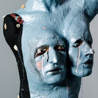 A blue painted and sculpted mannequin with two faces in the chest area