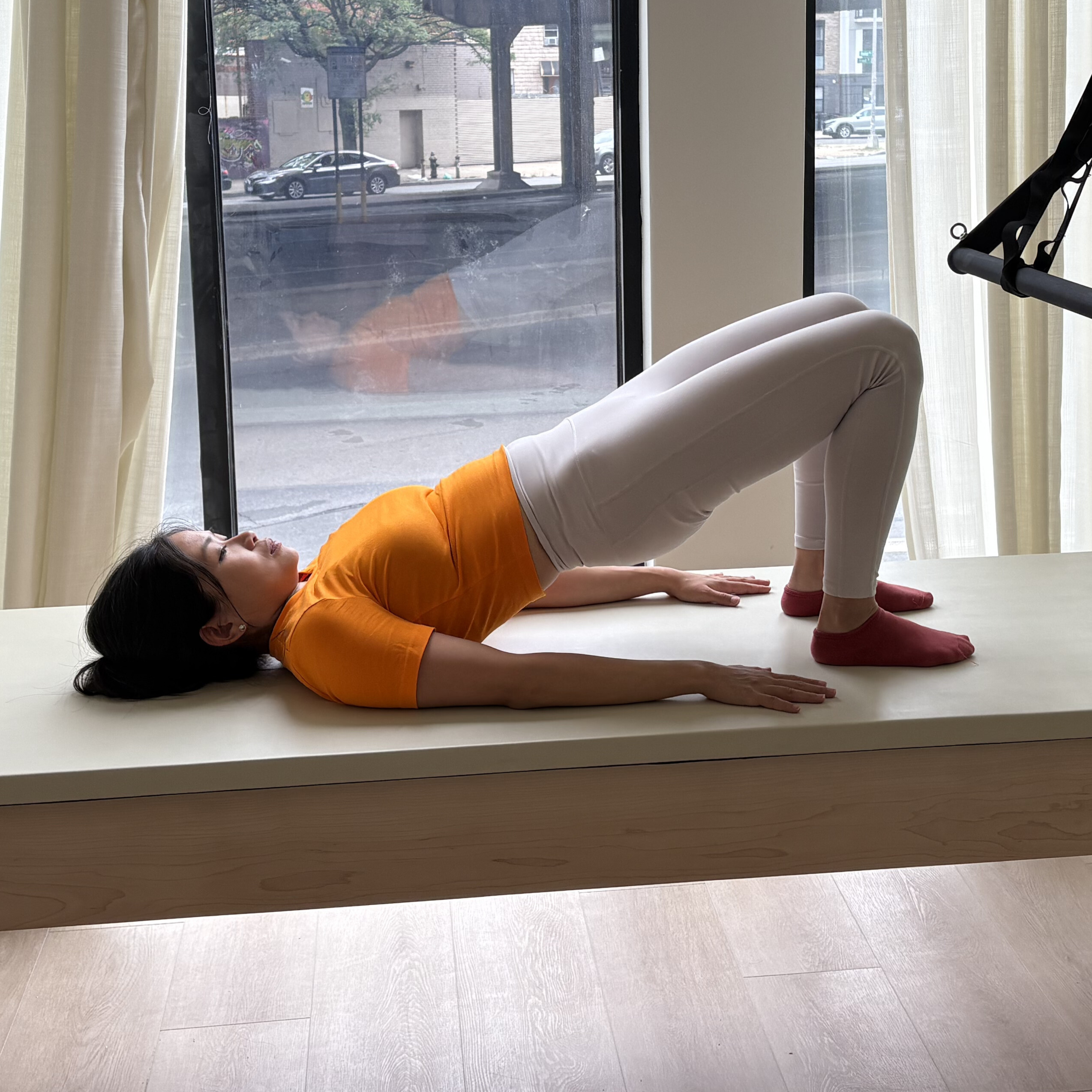 Woman demonstrates exercise on reformer bed