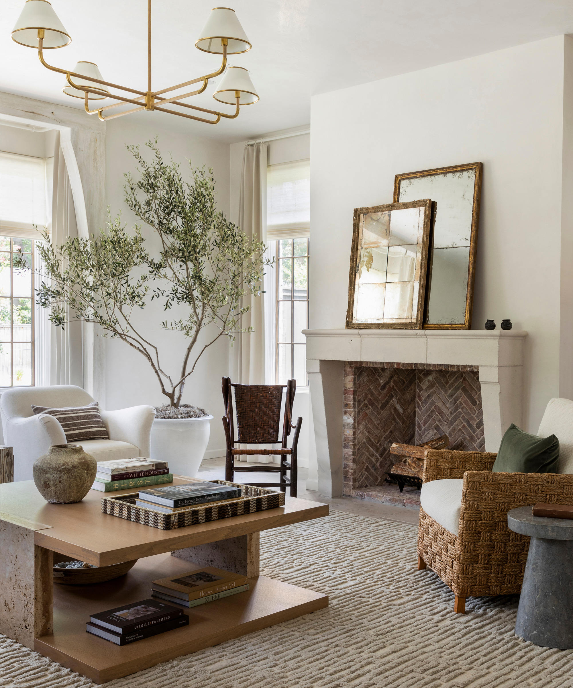A sitting room with neutral furniture, white walls and an olive tree