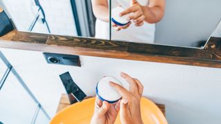 A woman holding a heavy cream-based moisturiser