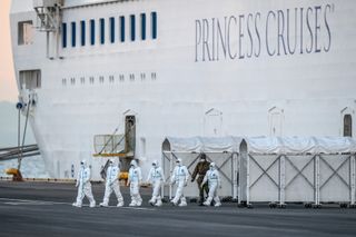 Emergency workers exit the Diamond Princess cruise ship where thousands remain quarantined.