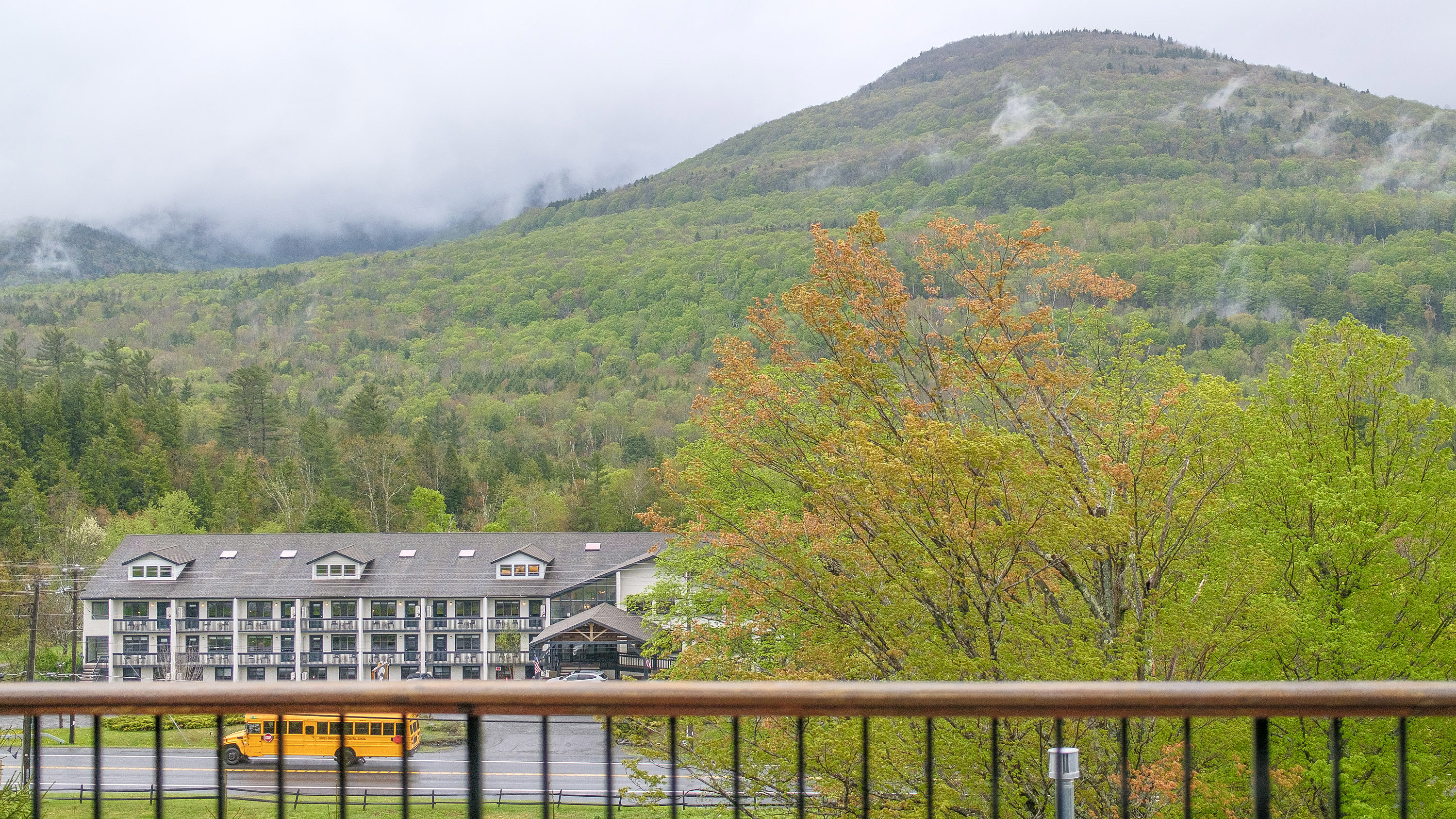 Scenic view of Hunter Mountain in upstate New York shrouded in fog with a yellow bus passing at the base