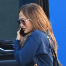 Jennifer lopez wears oversize sunglasses and a navy sweatshirt.