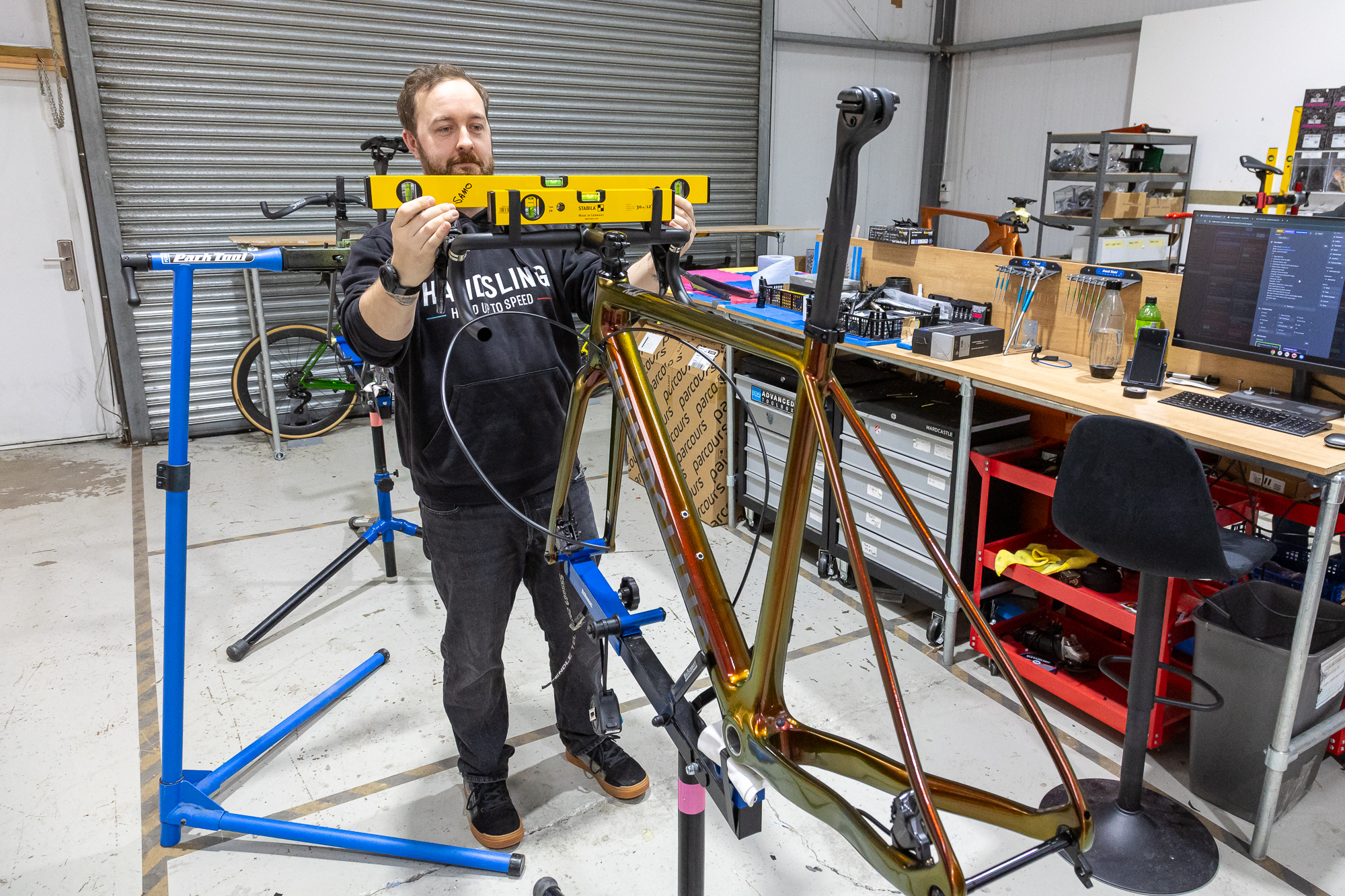 Bike mechanic checking the handlebar level on a frame being built up in a workshop