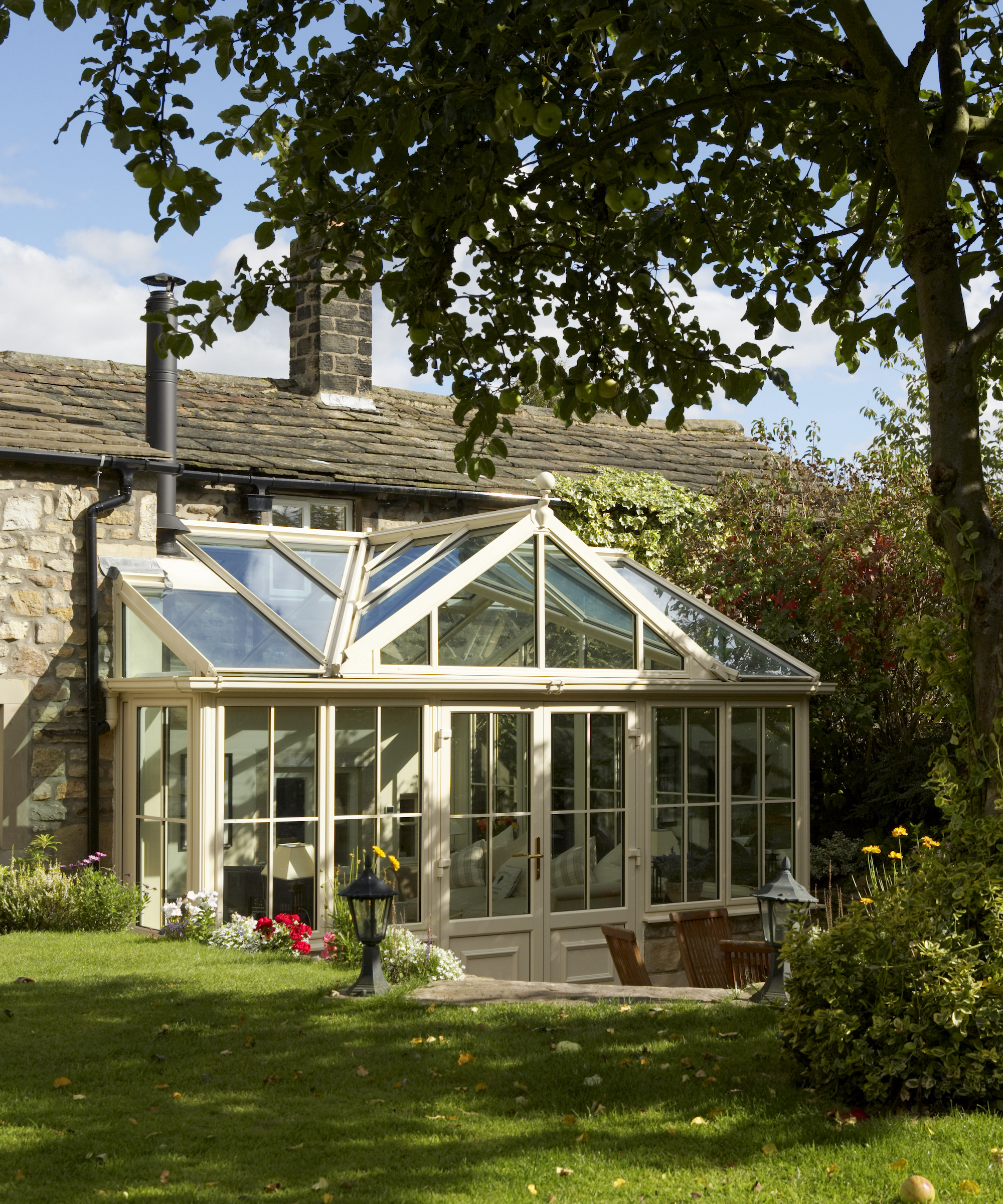Conservatory at rear of cottage with terrace and lawn beyond
