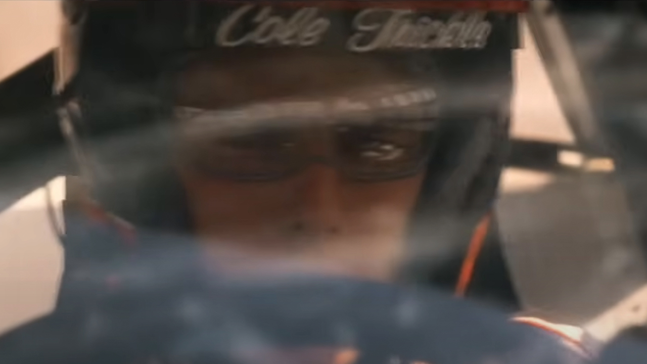 Tom Cruise driving a race car, wearing a helmet that says Cole Trickle in Days Of Thunder