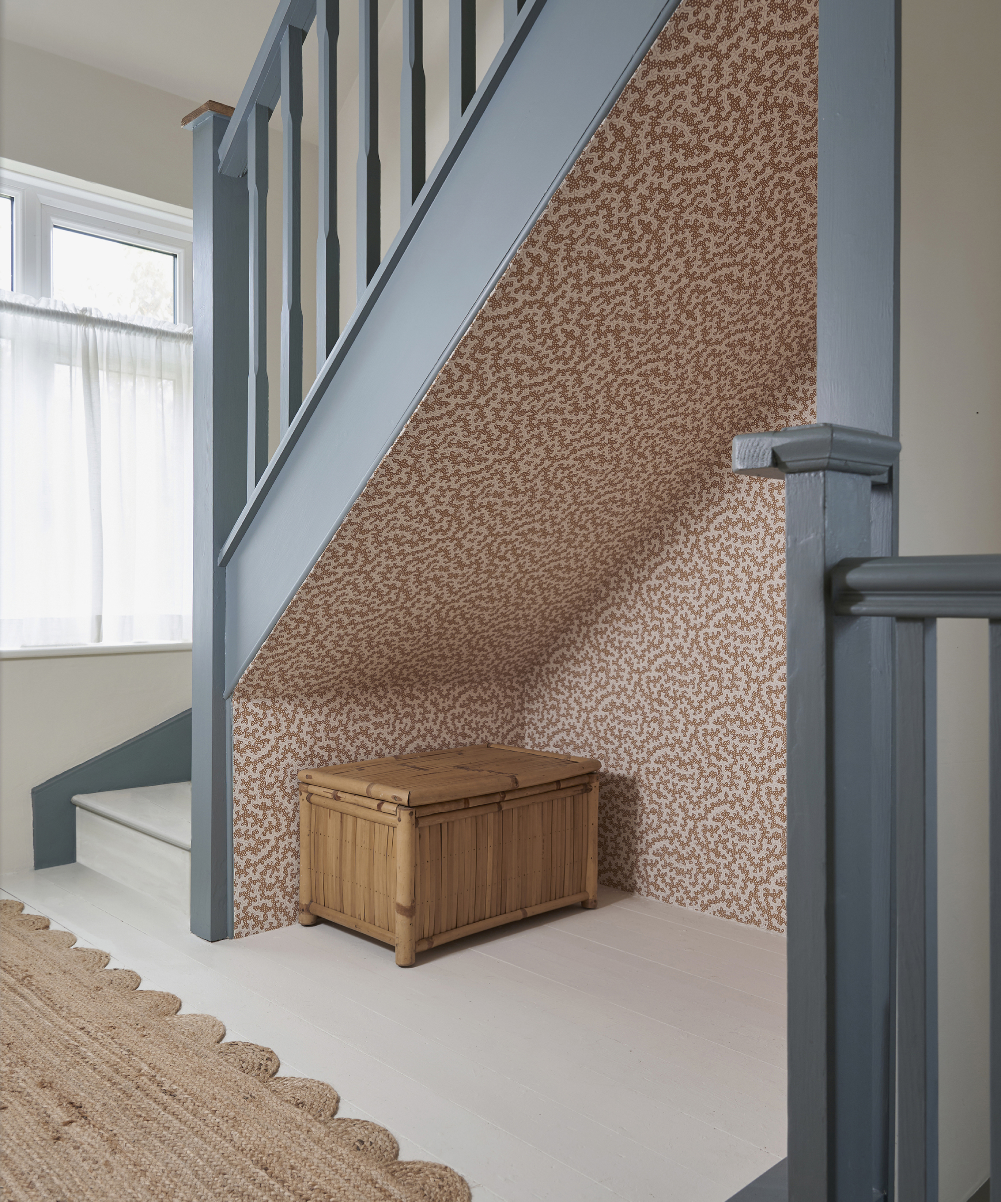 blue painted staircase with white treads and understairs alcove with pink patterned wallpaper