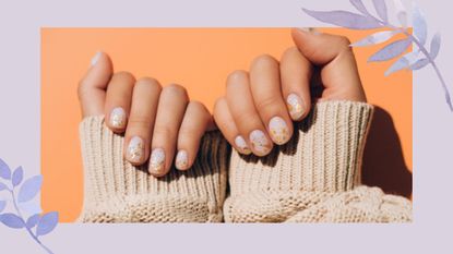Image of hands with speckled Easter nails against orange background 