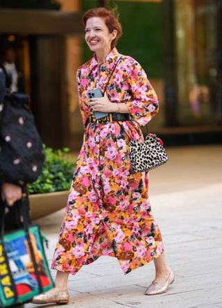 A woman wearing a floral patterned dress with a leopard print bag.