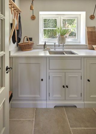 White shaker laundry room with large format stone flooring