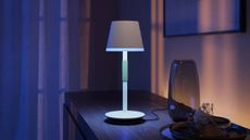 Philips Hue Go Table lamp sitting on a desk illuminating in the dark
