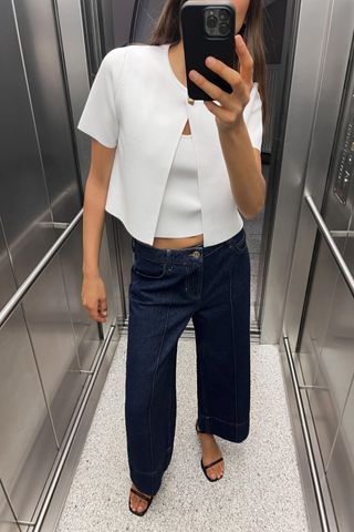 model wears white crop top and jeans and black heels