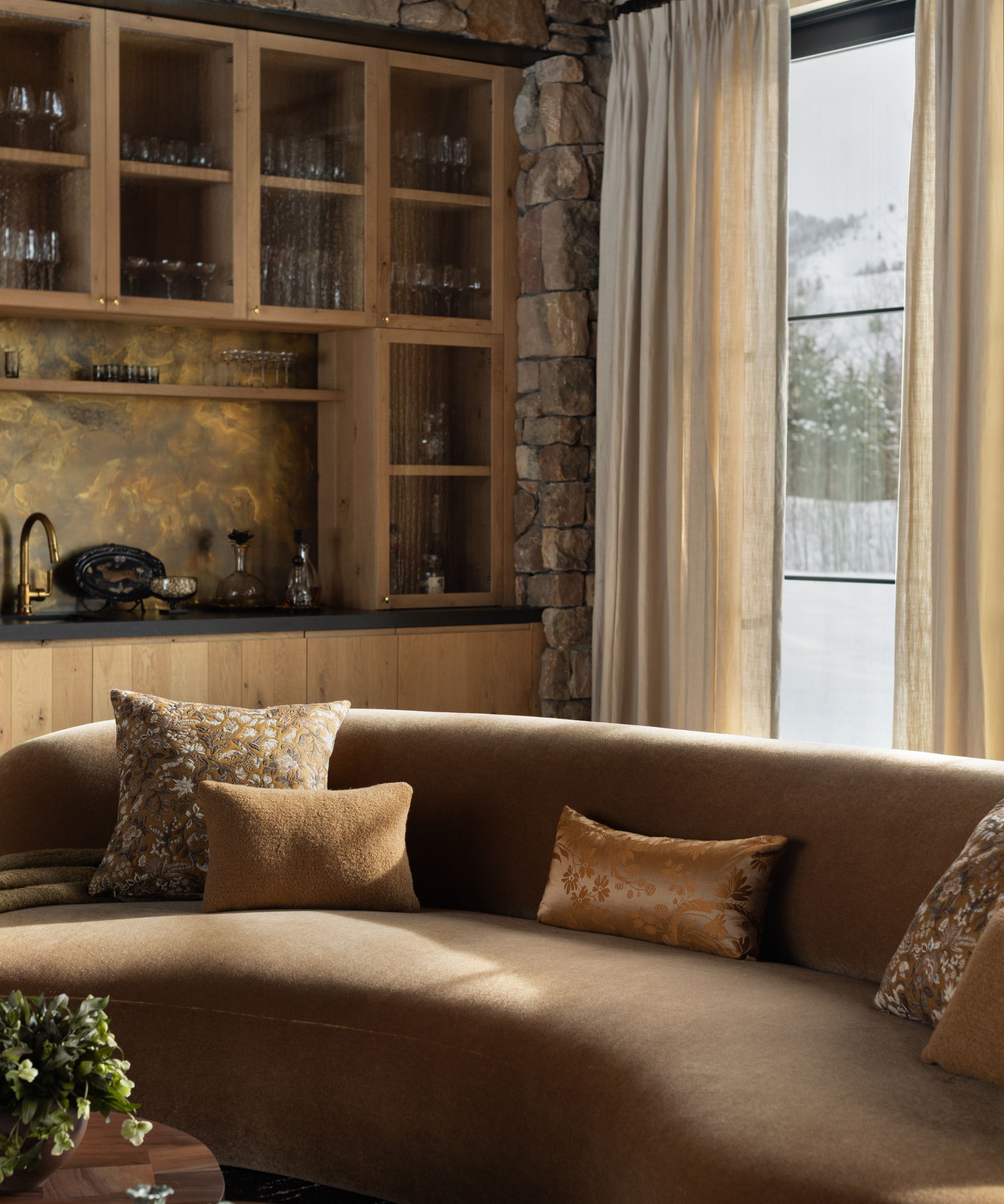 a large Great Room in Idaho with a vaulted ceiling, stone clad walls, oak home bar and curved velvet couch