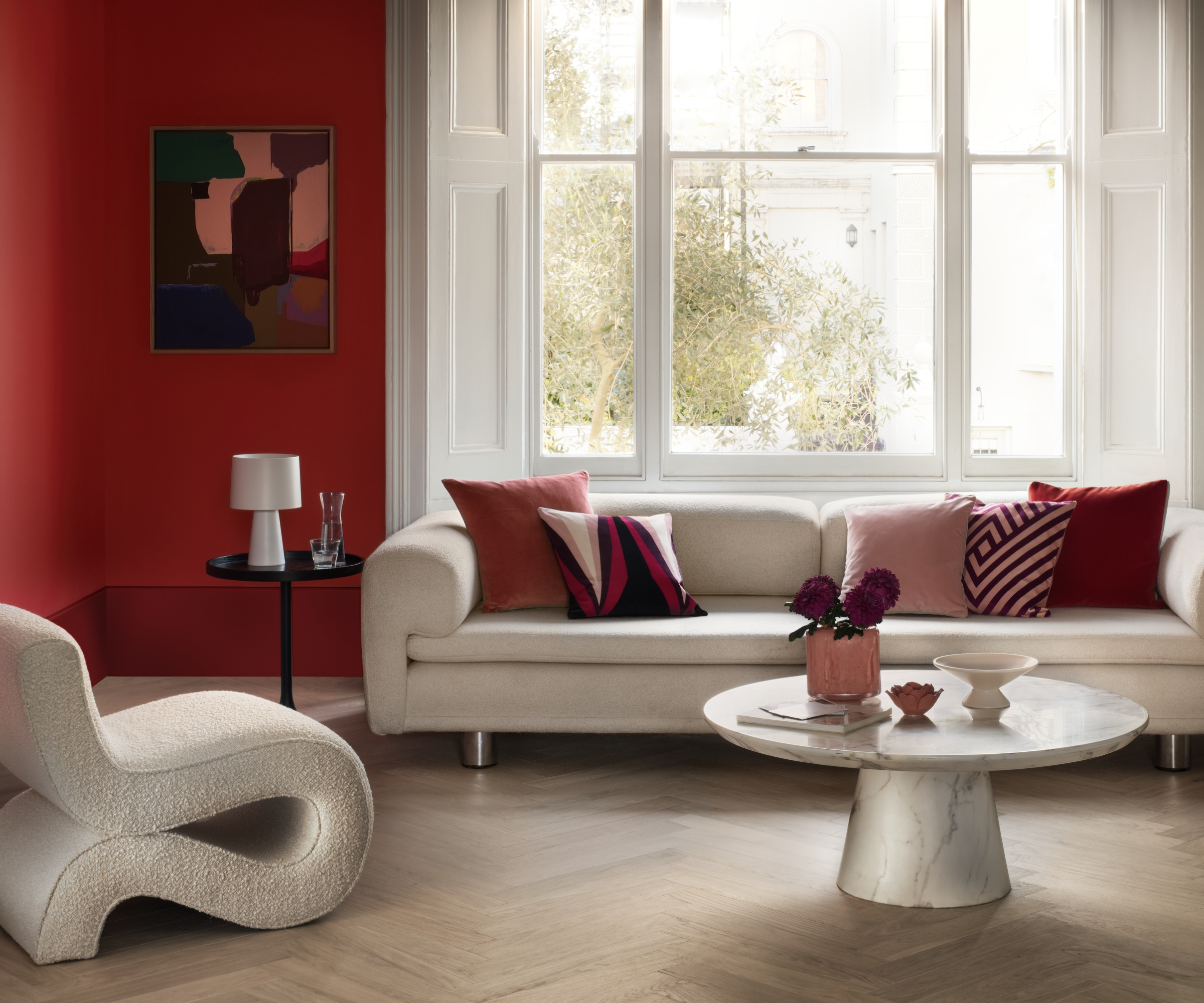 living room with red walls, cream sofa and chair, light wooden floor