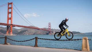 Danny MacAskill riding along a chain with Golden Gate Bridge behind