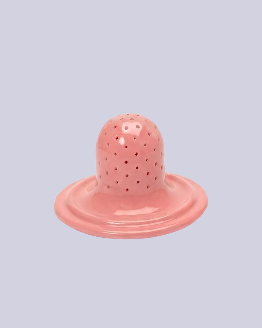 Chunky Ceramic Tea Strainer in pink againt pale purple background.