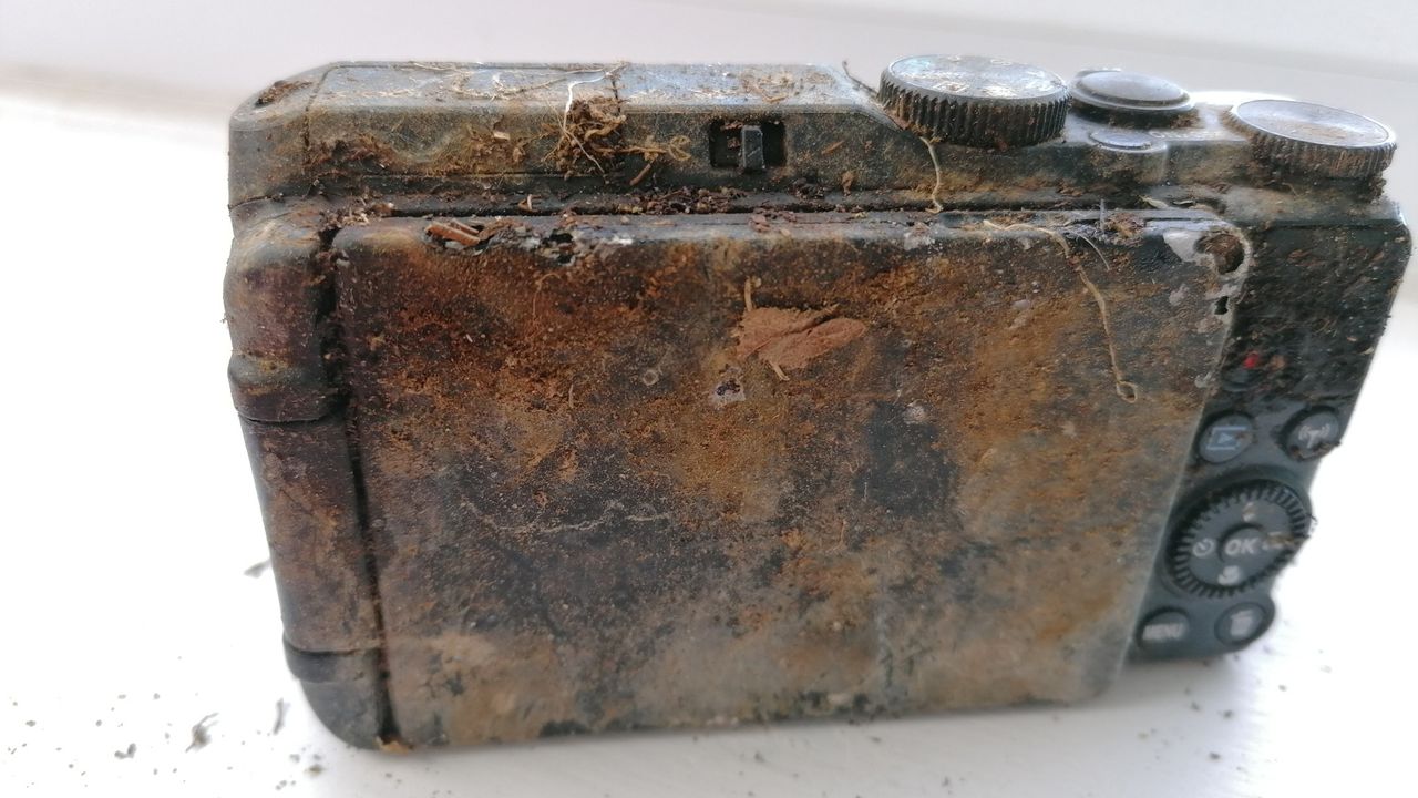 A heavily dirt-covered Nikon Coolpix S9900 displaying signs of neglect, with grime and debris on the surface and buttons