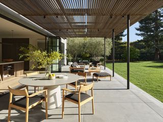 covered patio leading onto an an open plan kitchen and large green backyard