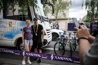Tiffany Cromwell and Valtteri Bottas stand next to each other in font of the Canyon//SRAM team bus at the Tour de France Femmes avec Zwift.