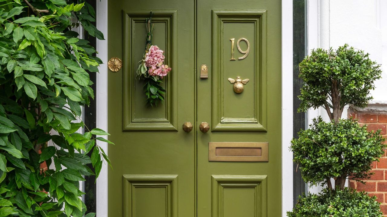 Close up of green front door with pink hanging flower decoration