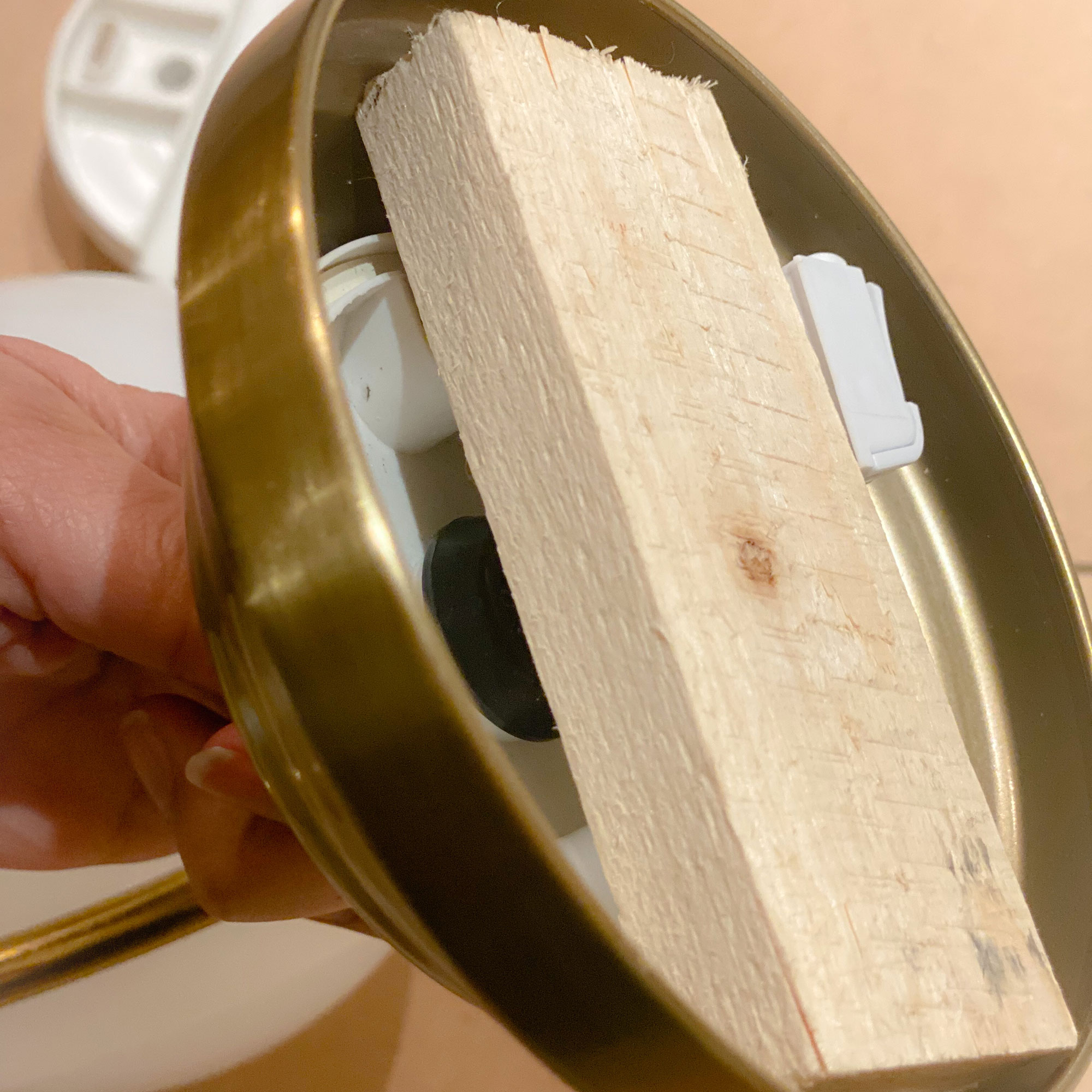 Small piece of wood attached to mount of wall light