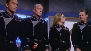 The command crew of Babylon 5 stand together smiling on the bridge.